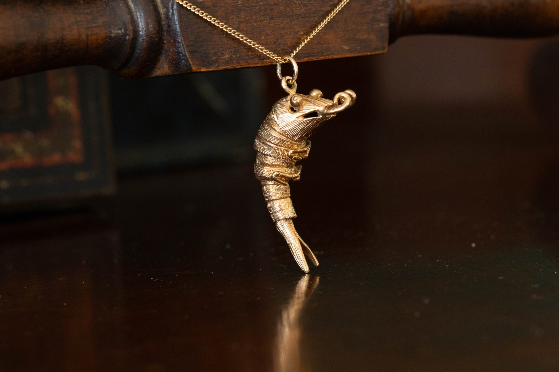 9ct yellow gold articulated shrimp pendant charm with segmented body hanging against a dark background.