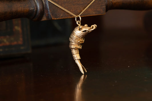 9ct yellow gold articulated shrimp pendant charm with segmented body hanging against a dark background.