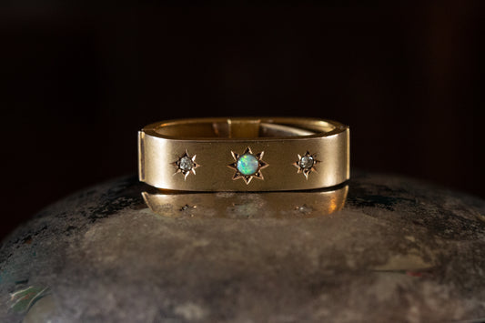 Front view of Edwardian 15ct yellow gold scarf clip featuring a central star-set opal flanked by two star-set diamonds.