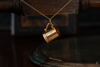 9ct yellow gold tankard pendant charm hanging against a dark background.