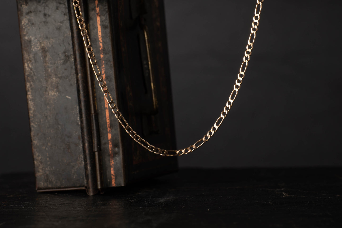 9ct rose gold vintage figaro link chain necklace hanging against a dark background.