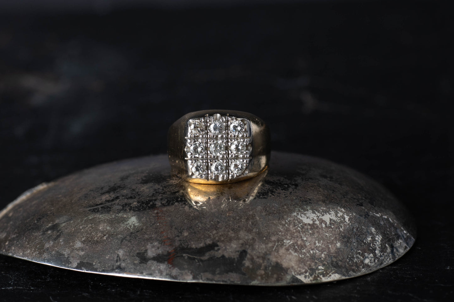 Gents 18ct yellow gold signet ring featuring a square face set with 9 brilliant cut diamonds on a dark reflective surface.