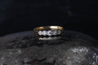 Vintage 18ct yellow gold and platinum ring featuring five graduated diamonds set in a row on a dark surface.