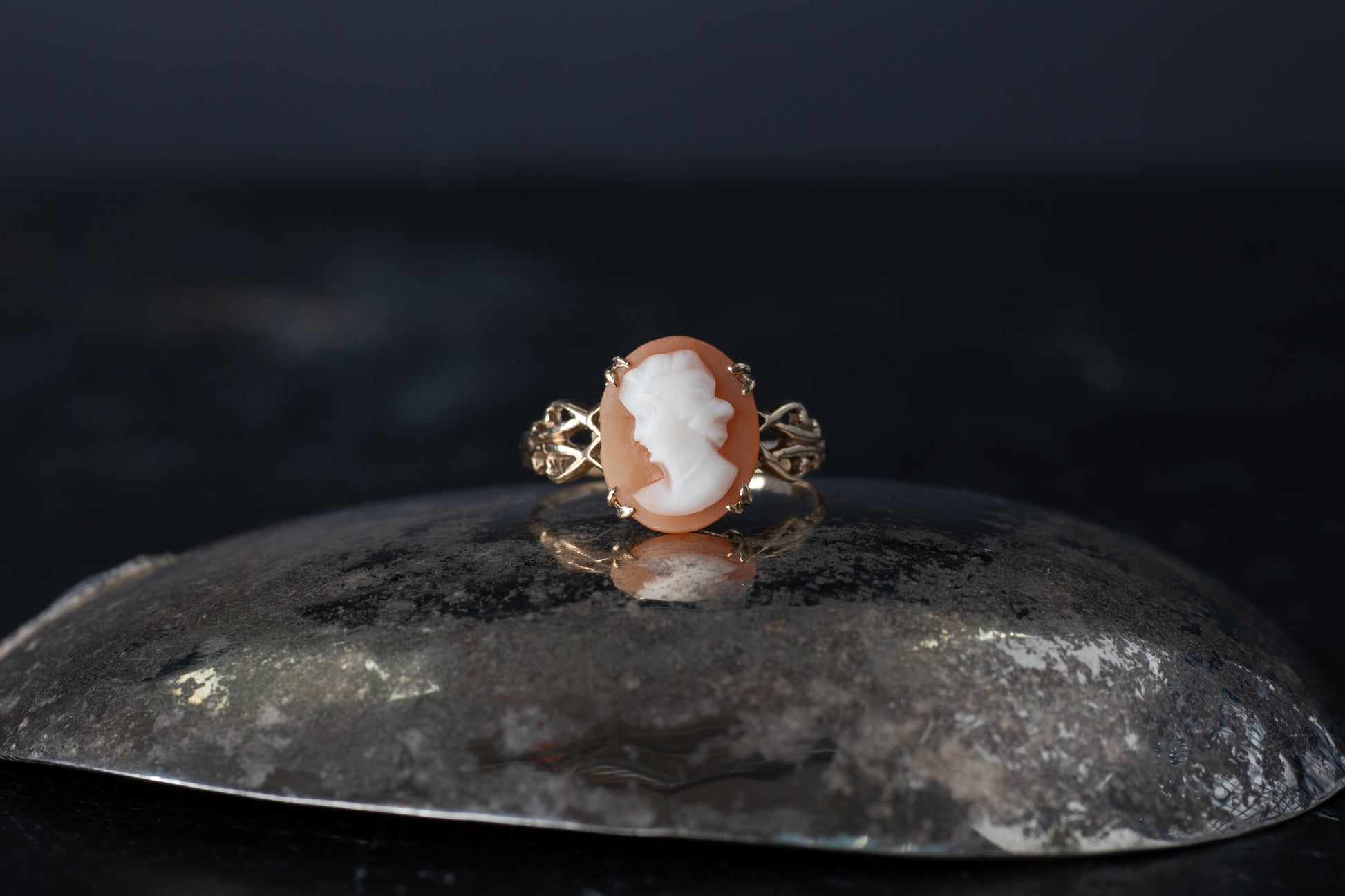 Vintage 9ct yellow gold ring featuring a claw set Mother of Pearl cameo profile on a dark reflective surface.
