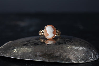 Vintage 9ct yellow gold ring featuring a claw set Mother of Pearl cameo profile on a dark reflective surface.