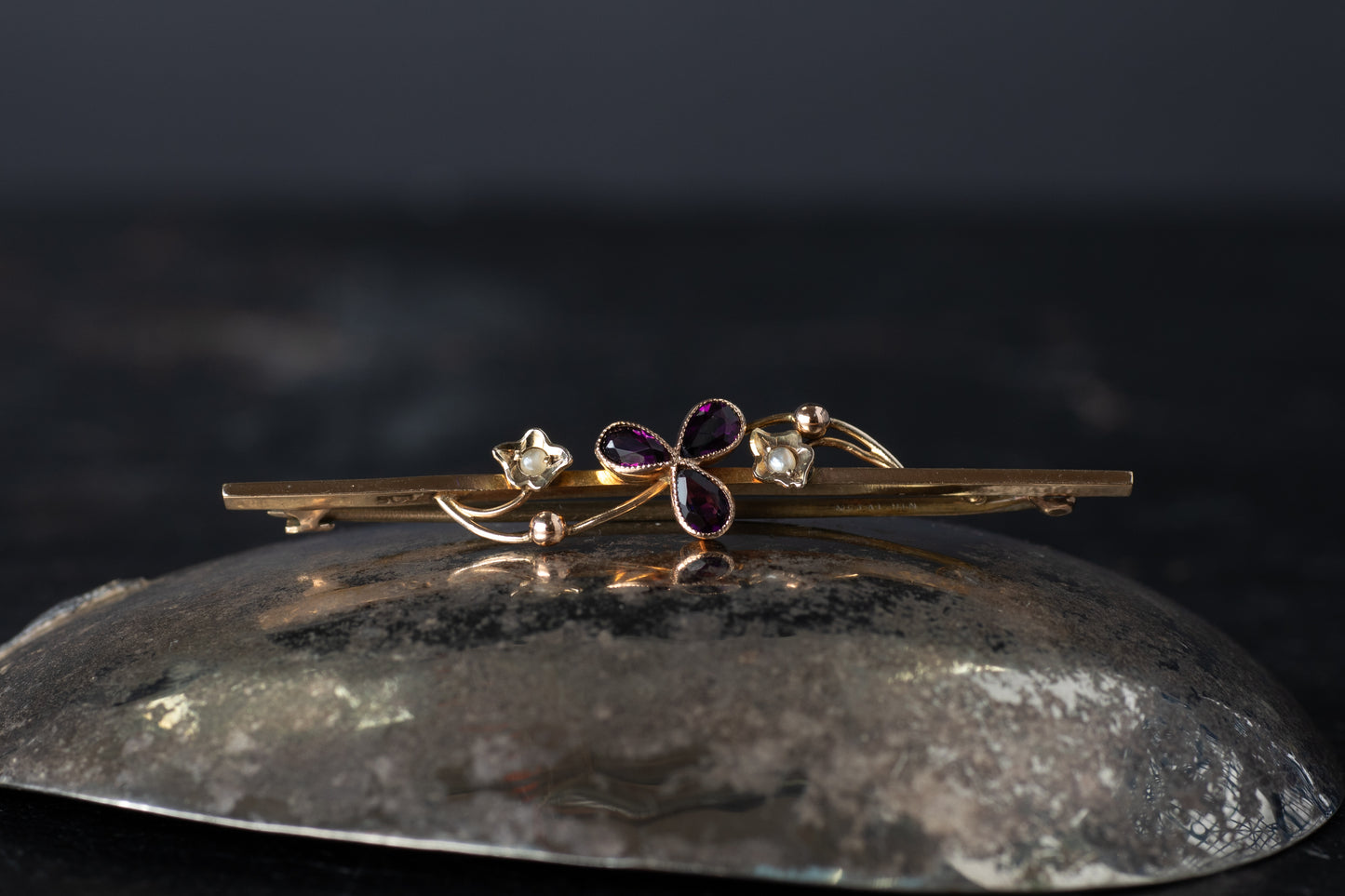 Vintage 9ct yellow gold bar brooch featuring a central amethyst trefoil and seed pearls with millegrain edging.
