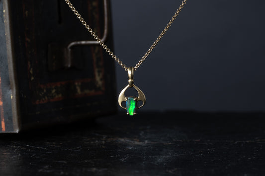 18ct yellow gold pendant featuring a rectangular opal doublet with vibrant green flash hanging against a dark vintage box.
