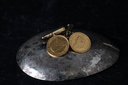 Pair of 22ct yellow gold cufflinks featuring 1896 South African half pound coins and bullet-shaped toggles.
