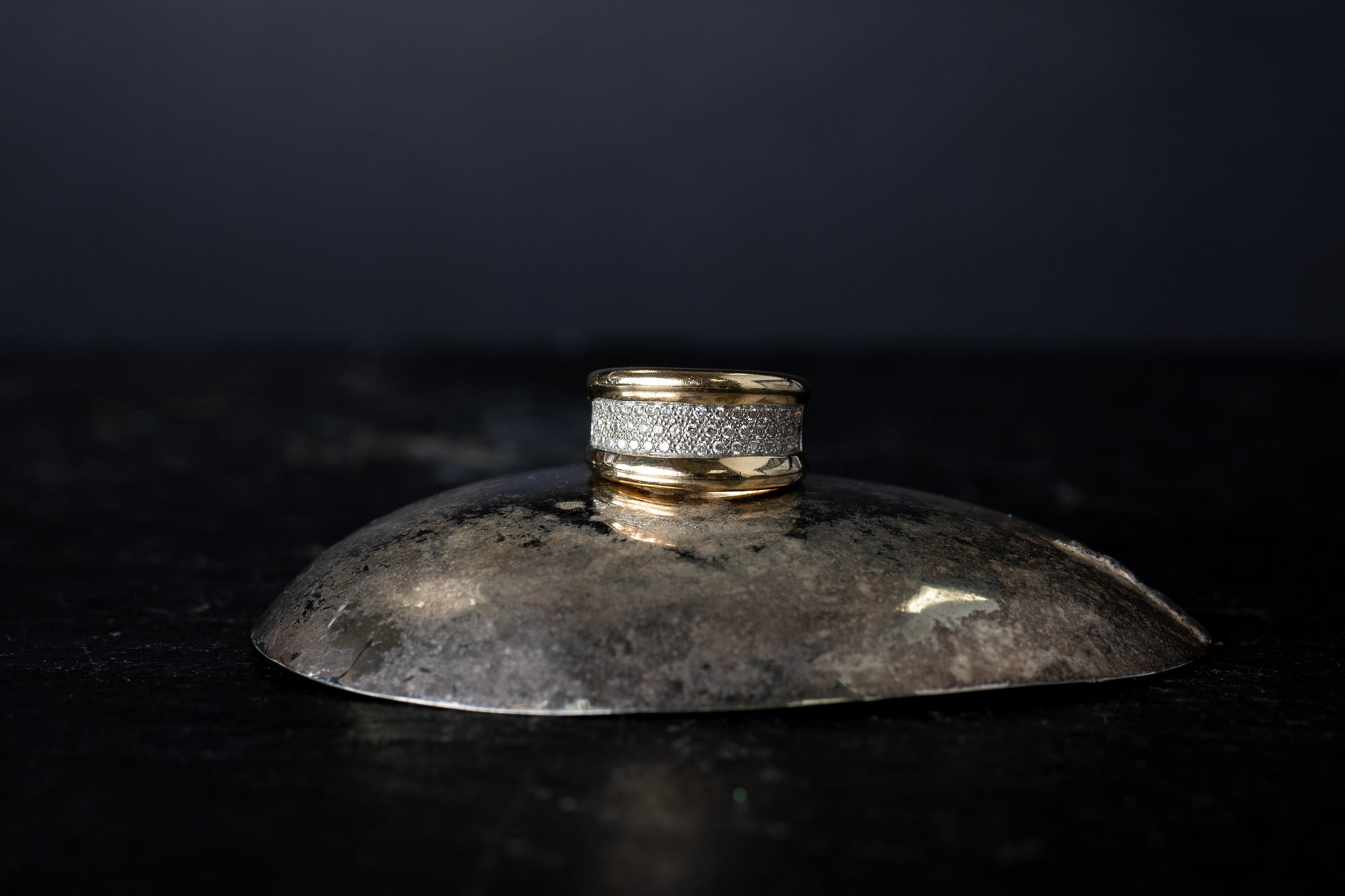 Wide 14ct yellow gold ring featuring a central section of pave set diamonds bordered by smooth gold edges on a dark surface.