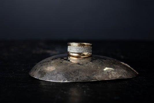 Wide 14ct yellow gold ring featuring a central section of pave set diamonds bordered by smooth gold edges on a dark surface.