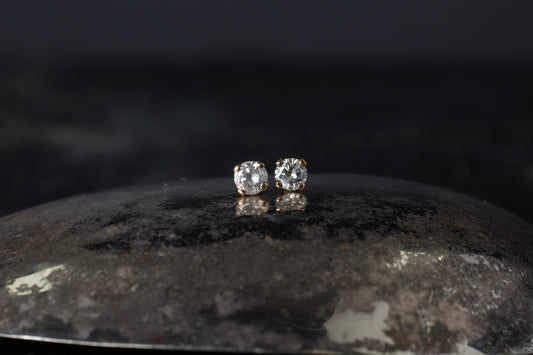 Pair of 9ct yellow gold stud earrings featuring brilliant cut diamonds claw set on a dark reflective surface.