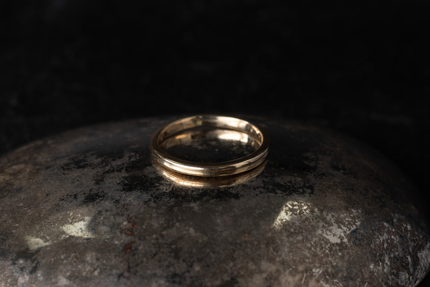 Classic 9ct yellow gold plain wedding band with a polished finish resting on a dark reflective surface.