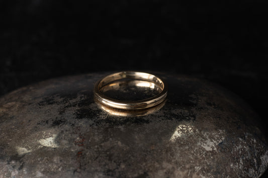 Classic 9ct yellow gold plain wedding band with a polished finish resting on a dark reflective surface.