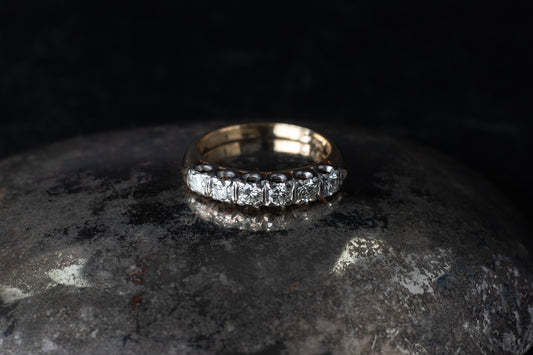 Vintage 14ct yellow gold half eternity ring featuring six brilliant cut diamonds set in a row on a dark reflective surface.