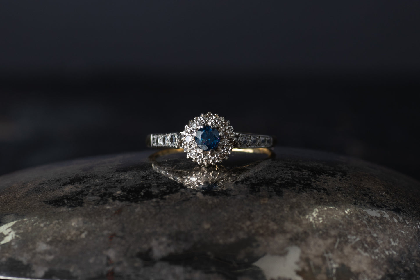 Vintage 18ct yellow gold and platinum ring featuring a central blue sapphire surrounded by a halo of old mine cut diamonds.