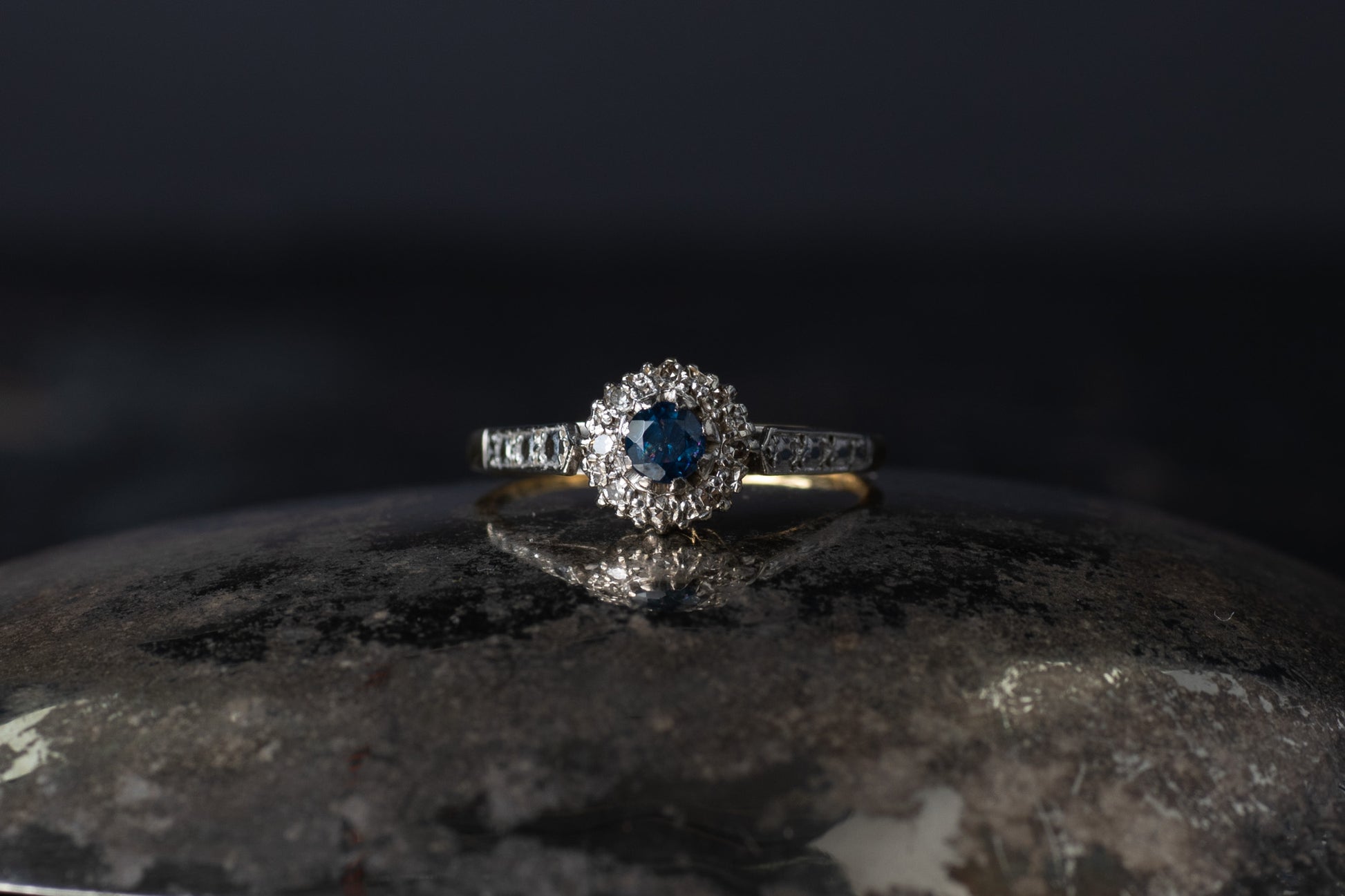 Vintage 18ct yellow gold and platinum ring featuring a central blue sapphire surrounded by a halo of old mine cut diamonds.