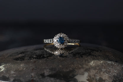Vintage 18ct yellow gold and platinum ring featuring a central blue sapphire surrounded by a halo of old mine cut diamonds.
