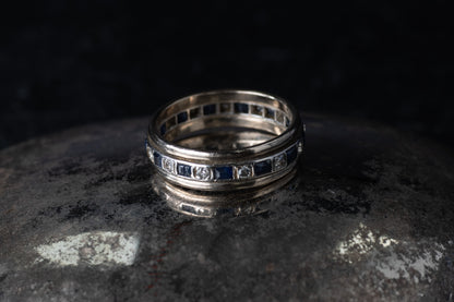 Antique platinum full eternity ring featuring alternating square blue sapphires and round diamonds set around the entire band.