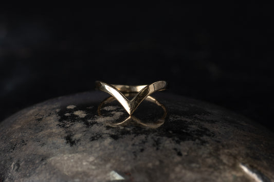 9ct yellow gold wishbone ring featuring a sleek V-shaped chevron design resting on a dark reflective surface.