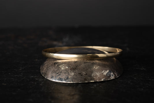 Eye-level view of 9ct yellow gold round bangle showcasing smooth curvature on dark stone background.