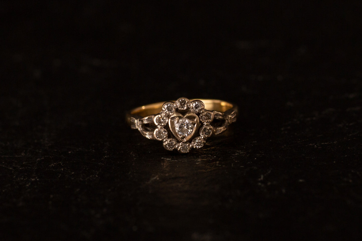 Front view of 18ct yellow and white gold ring featuring a diamond heart cluster setting on a dark background.