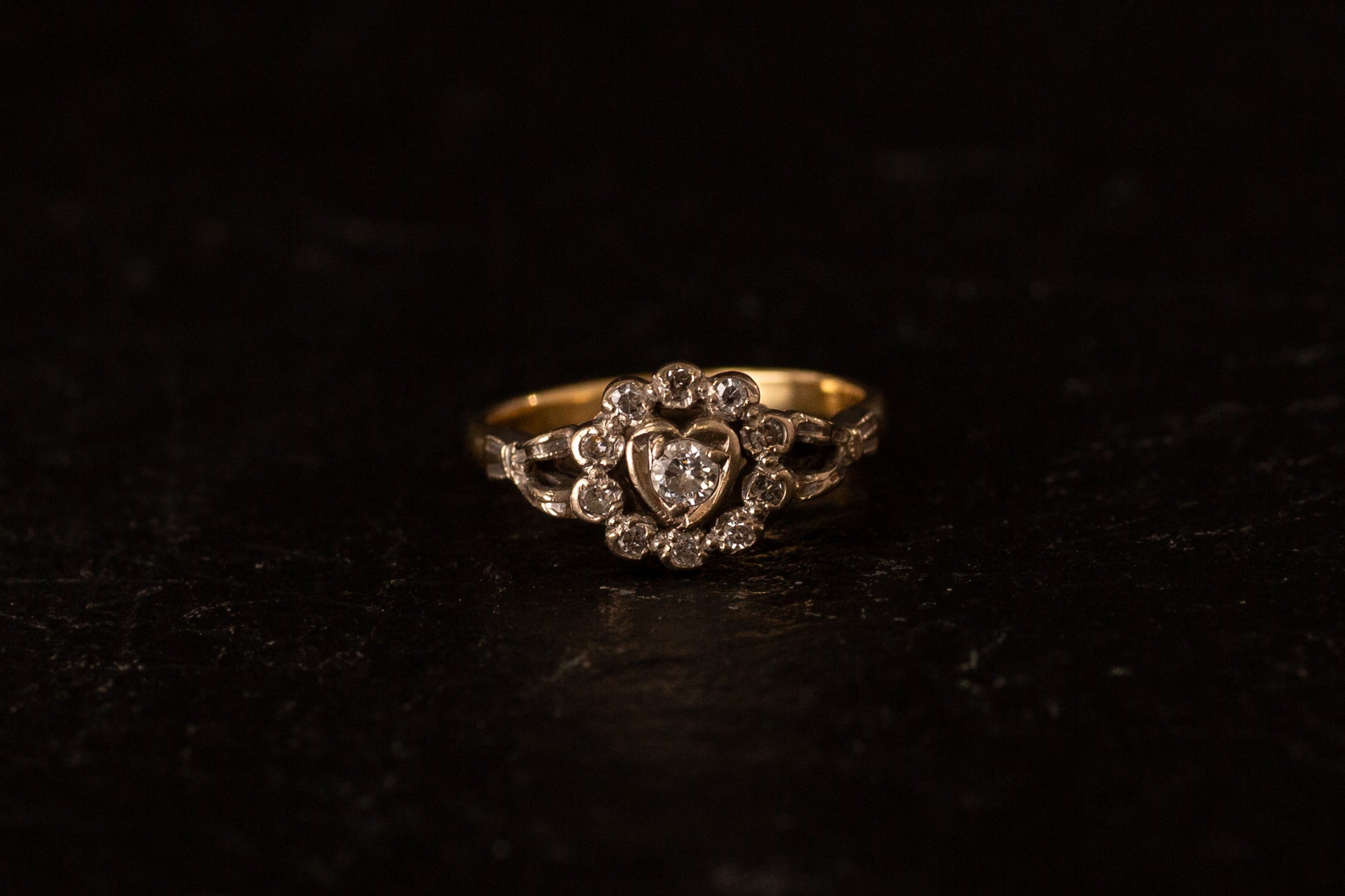 Front view of 18ct yellow and white gold ring featuring a diamond heart cluster setting on a dark background.