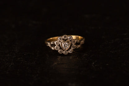 Front view of 18ct yellow and white gold ring featuring a diamond heart cluster setting on a dark background.
