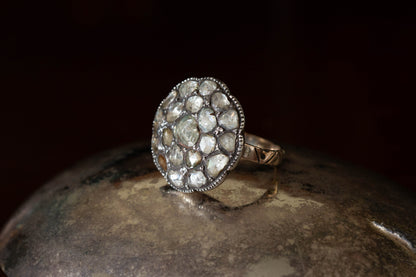 Side angle of sterling silver cluster ring featuring large circular rose cut diamonds with millegrain setting on dark prop.