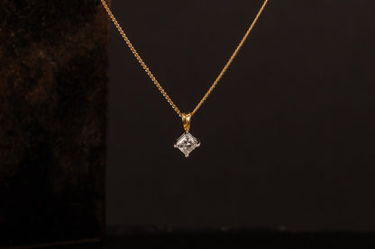 Front view of 18ct gold princess cut diamond solitaire pendant hanging against a dark background.