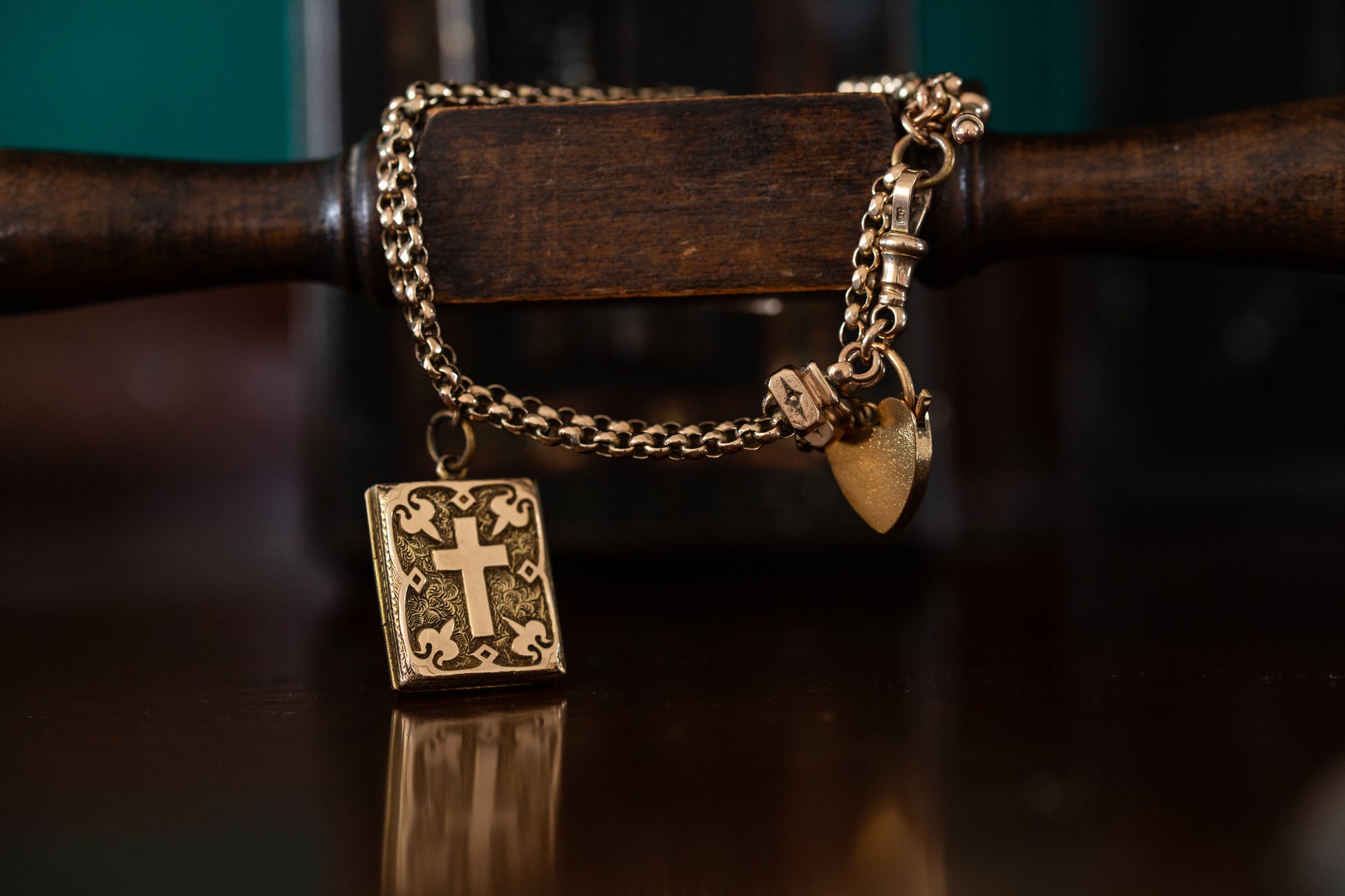 Front view of antique 9ct rose gold guard chain bracelet featuring a heart padlock clasp and a rectangular bible charm with a cross.