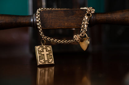 Front view of antique 9ct rose gold guard chain bracelet featuring a heart padlock clasp and a rectangular bible charm with a cross.