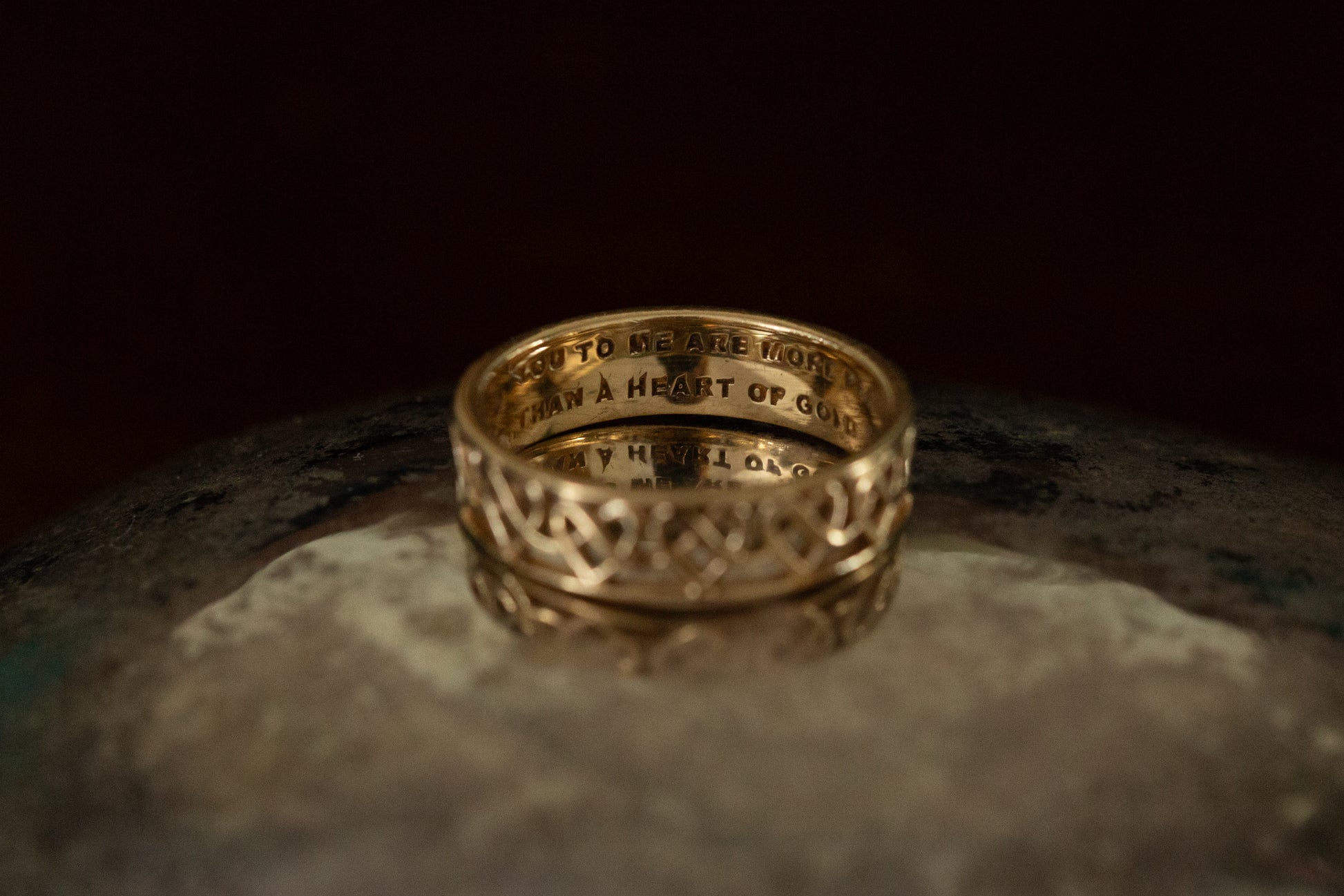 Gold ring with engraved text on a dark surface